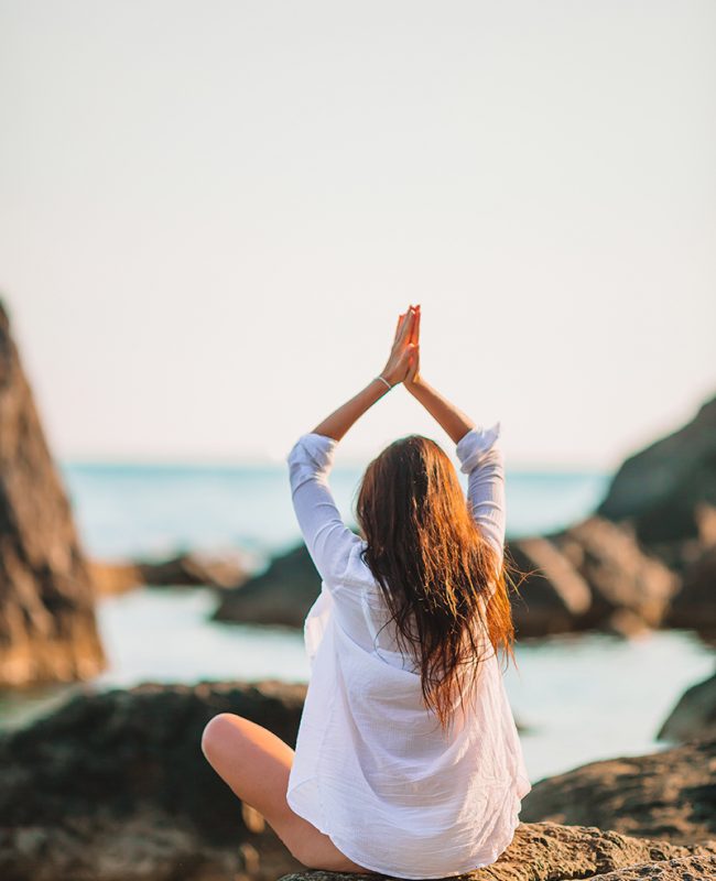 Young beautiful woman woman practicing yoga at seashore